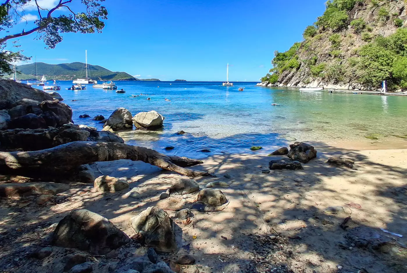 Petite plage abritée aux eaux claires au pied du Pain de Sucre, à Terre-de-Haut, avec des nageurs au masque et tuba