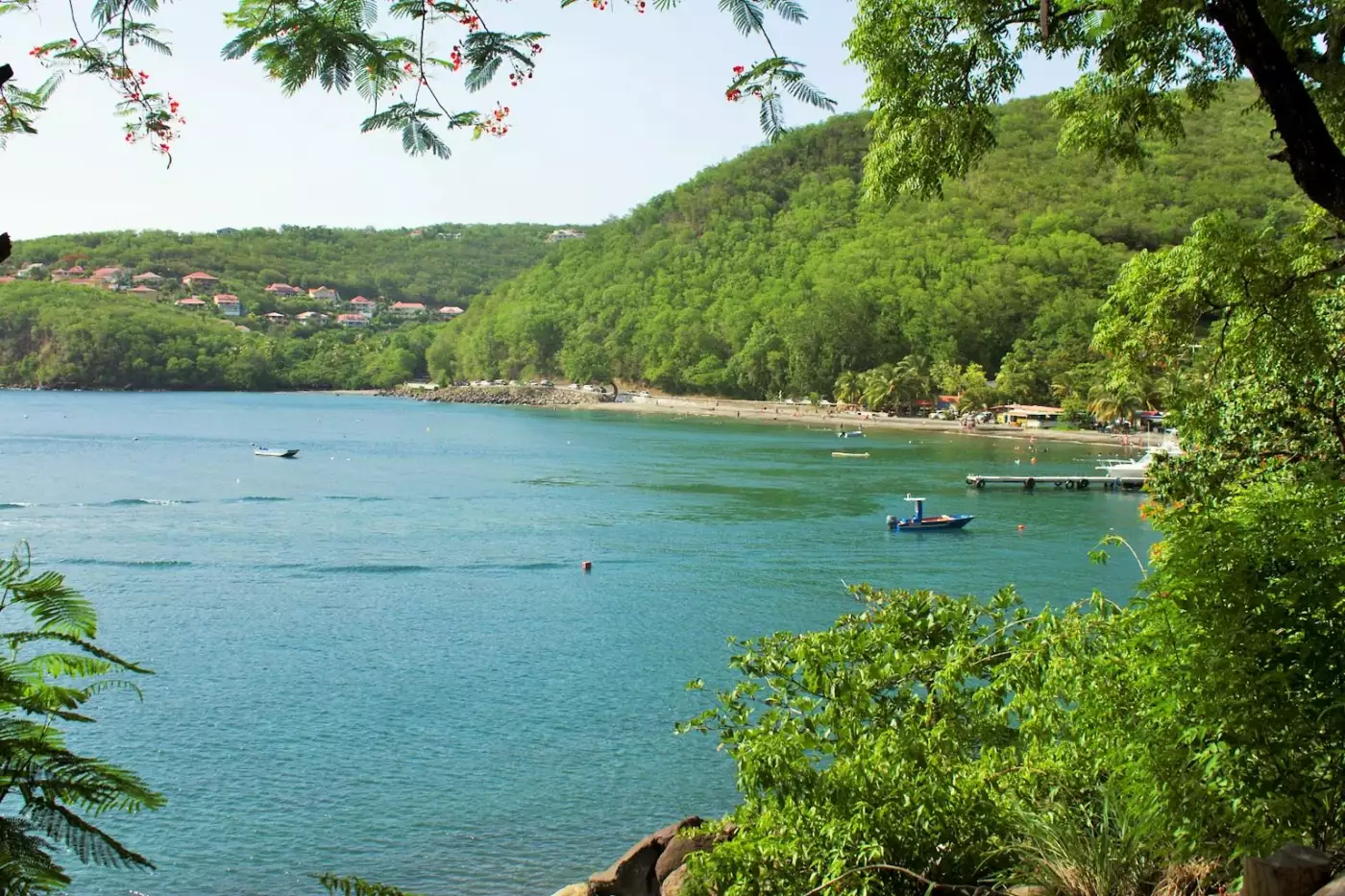 Baie de Malendure à Bouillante, bateaux au mouillage devant la plage de sable sombre et mornes boisés