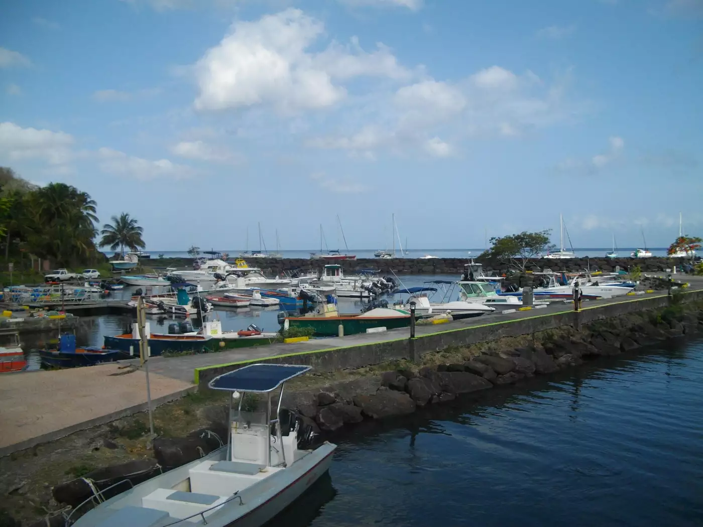 Bateaux de pêche abrités derrière la digue du port de Deshaies et voiliers au mouillage dans la baie