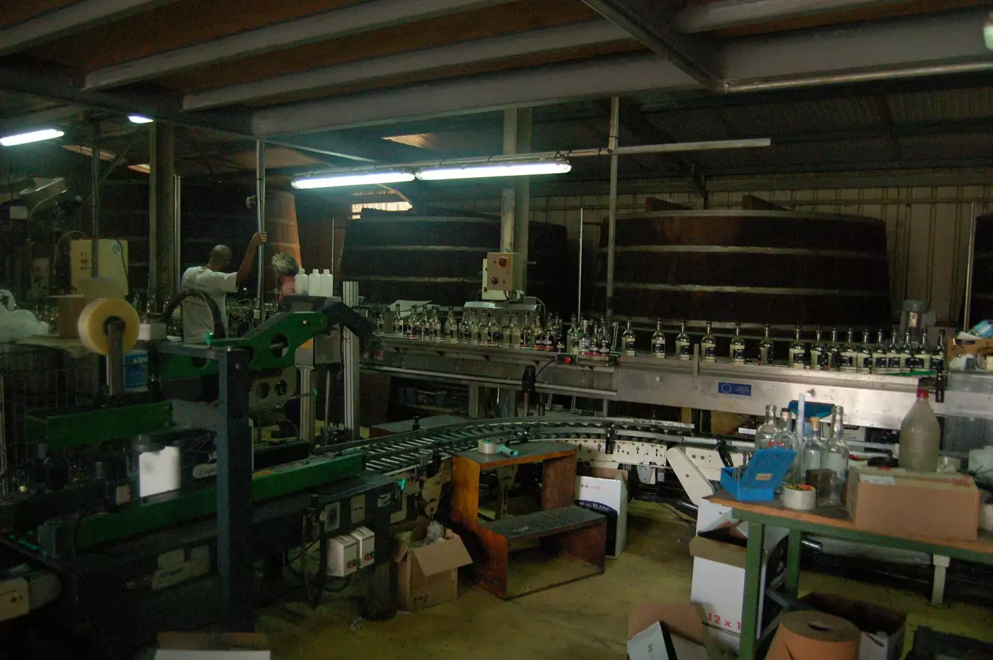 Chaîne d'embouteillage et grandes cuves en bois à l'intérieur de la distillerie Damoiseau, au Moule