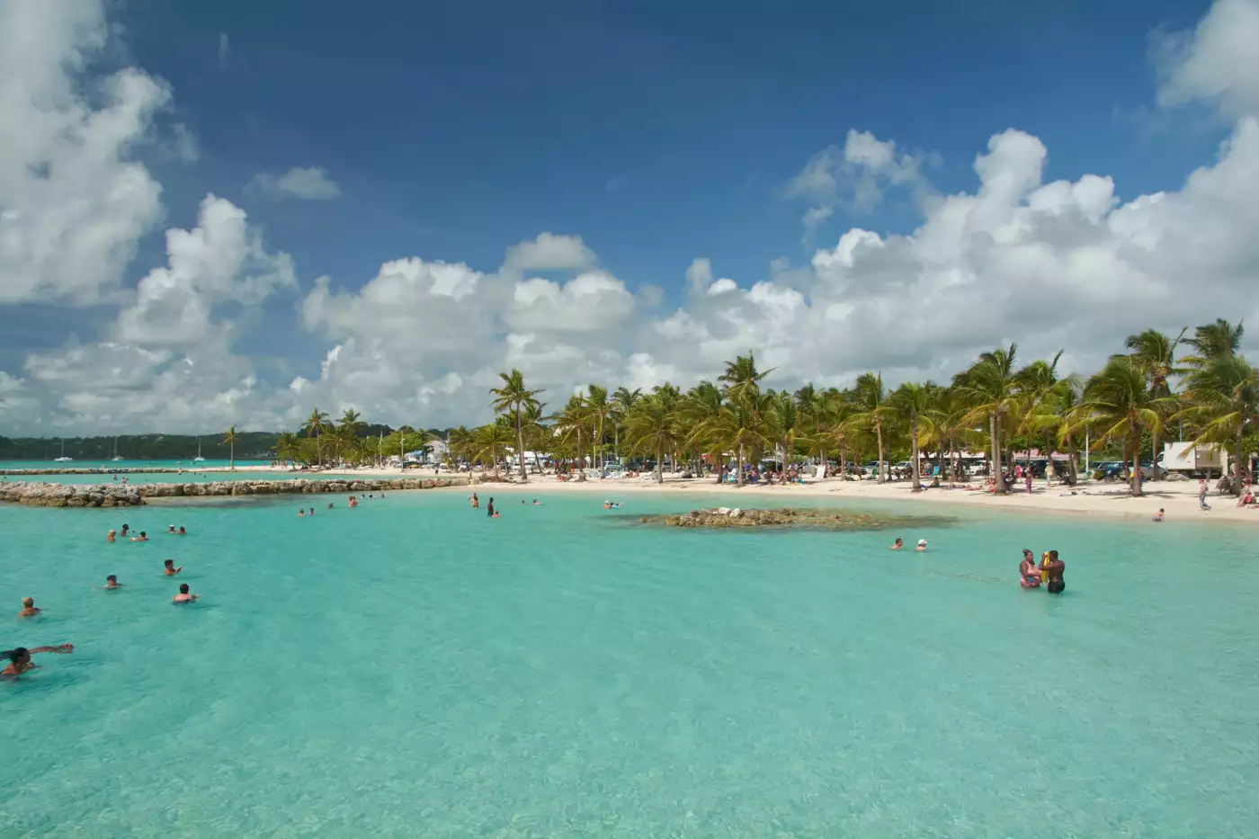 Lagon turquoise peu profond, baigneurs et cocotiers sur la plage de Sainte-Anne, en Guadeloupe
