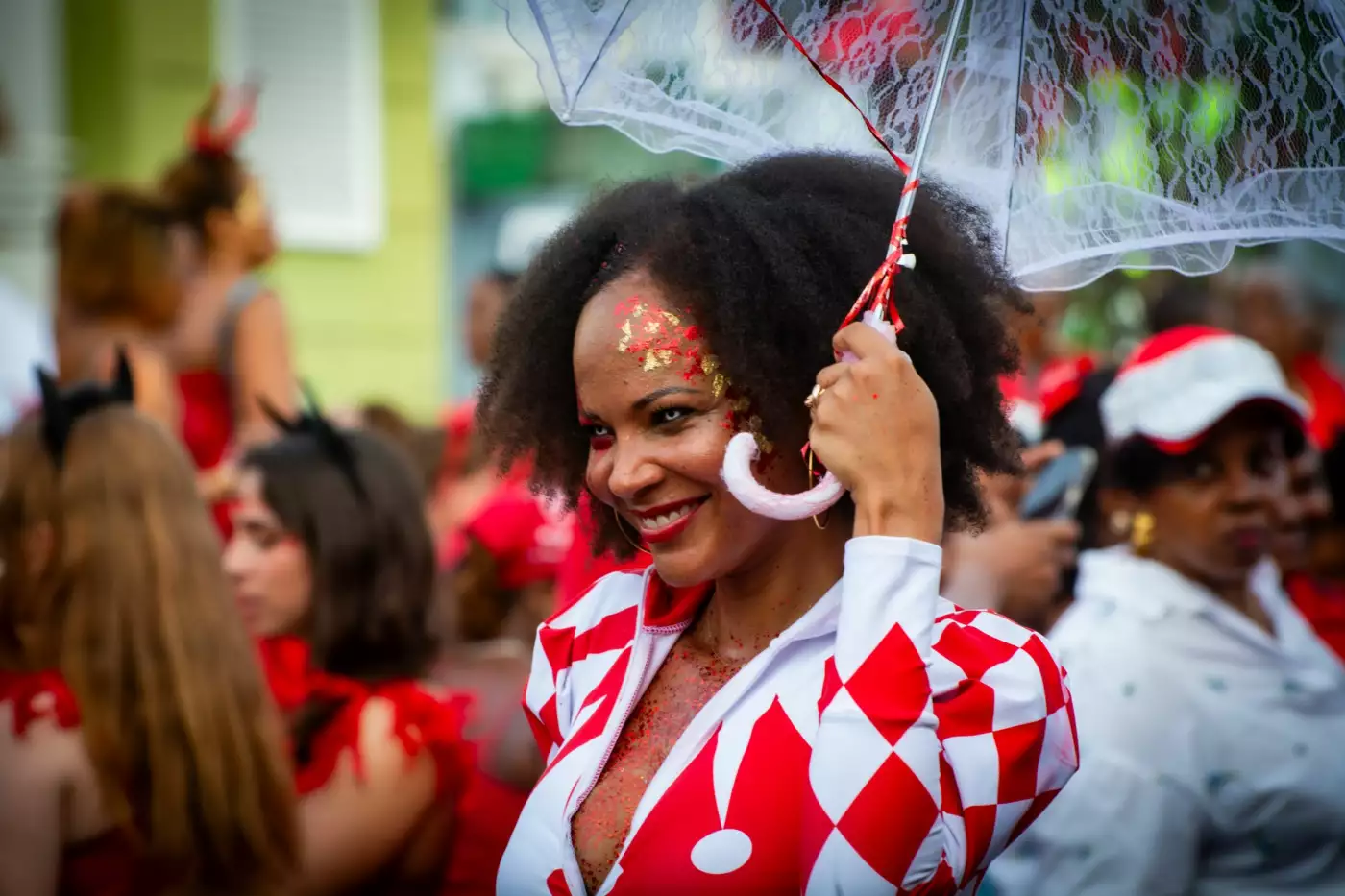 Participante souriante en costume de carnaval avec parapluie décoré au milieu d'un défilé
