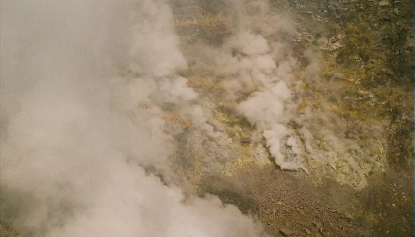 Fumerolles s'échappant d'un cratère de volcan actif au terrain nu et accidenté